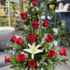Tall arrangement of red roses and a white lily in a white vase