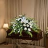 A serene all-white casket spray that gives a deeply respectful, comforting presence