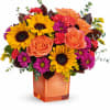 Colorful bouquet of sunflowers, roses, and daisies in an orange vase
