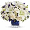 White lilies and roses arranged in a blue glass vase
