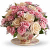 Pink and cream roses arranged in a floral teacup on a saucer