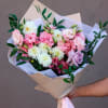 Hand-tied bouquet of pink and white flowers wrapped in beige paper
