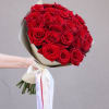 Bouquet of red roses wrapped in cream paper with a white ribbon