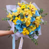 Bouquet of blue roses, yellow orchids, and small yellow blooms wrapped in white paper