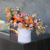 Large mixed floral arrangement in a white vase with pink and orange blooms