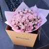 Bouquet of pale pink roses wrapped in pink paper inside a gift box