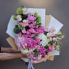 Handheld bouquet of pink and white flowers wrapped in paper