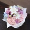 Bouquet of white lilies, pink chrysanthemums, and blue hydrangeas in white wrap
