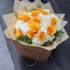 Bouquet of orange roses and white hydrangeas in tan wrapping