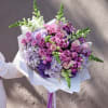Bouquet of pink, purple, and white flowers wrapped in white paper