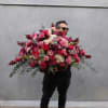 Man holding a huge mixed pink and red flower arrangement