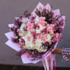 Pink roses and white hydrangeas in a wrapped bouquet with purple accents