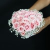 Handheld bouquet of pale pink roses with white baby's breath