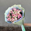 Hand-tied bouquet of pink and blush roses wrapped in pale green paper