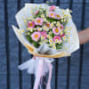 Pink daisy bouquet wrapped in white paper with a pink ribbon