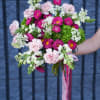 Handheld bouquet of pink and white flowers with a pink ribbon