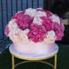 Large pink and white hydrangea arrangement in a round box on a gold table