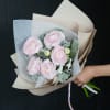 Hand-tied bouquet of pale pink ranunculus in beige and white paper