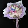 Bouquet of pink roses, hydrangeas, and white flowers wrapped in lavender paper