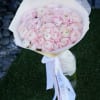 Bouquet of pale pink ranunculus wrapped in white paper with ribbon