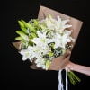 Bouquet of white lilies and baby's breath wrapped in brown paper
