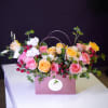 Pink and yellow roses arranged in a mauve gift bag