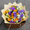 Bouquet of purple, orange, yellow, and white roses in cream wrapping