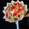Bouquet of peach roses and orange gerbera daisies wrapped in pink paper