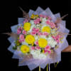 Bouquet of pink roses, yellow blooms, and white flowers wrapped in lavender paper