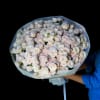 Large bouquet of pale pink and white roses wrapped in light paper