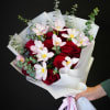 Bouquet of red roses and pale pink tulips wrapped in white paper