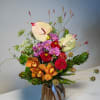 Colorful mixed bouquet with orchids, anthuriums, and dahlias in a wrapped base