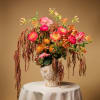 Tall floral arrangement in a textured vase with pink and orange blooms