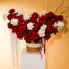 Red and white roses arranged in a woven basket with ribbon accents