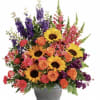 Mixed bouquet with sunflowers, orange roses, and purple spikes in a gray vase