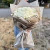 Bouquet of white roses wrapped in beige paper with a white ribbon