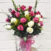 Bouquet of pink and white roses with small purple flowers in a wrapped vase