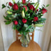 Red roses and lily buds arranged in a clear glass vase