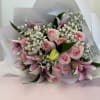 Pink roses and lilies with white baby's breath in wrapped bouquet