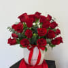 Red roses arranged in a white hatbox with a red ribbon