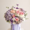 A lush cluster of pink roses and lavender hydrangeas makes a soft