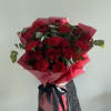 Bouquet of red roses and carnations wrapped in pink paper with a black ribbon