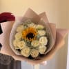 Hand-tied bouquet with a central sunflower surrounded by white roses in blush wrapping paper