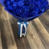Bouquet of vivid blue roses wrapped in blue paper with a ribbon