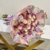 Bouquet of pink, cream, and lavender roses wrapped in pale pink paper