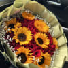 Bouquet of red roses and yellow sunflowers wrapped in pale paper