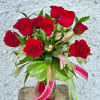 Red roses in a glass vase with pink ribbons