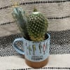 Two small cacti in a light blue mug with fishing graphics