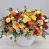 Mixed bouquet of yellow, orange, and red flowers in a white vase