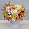 Mixed bouquet of pastel and bright flowers in a white cylindrical vase